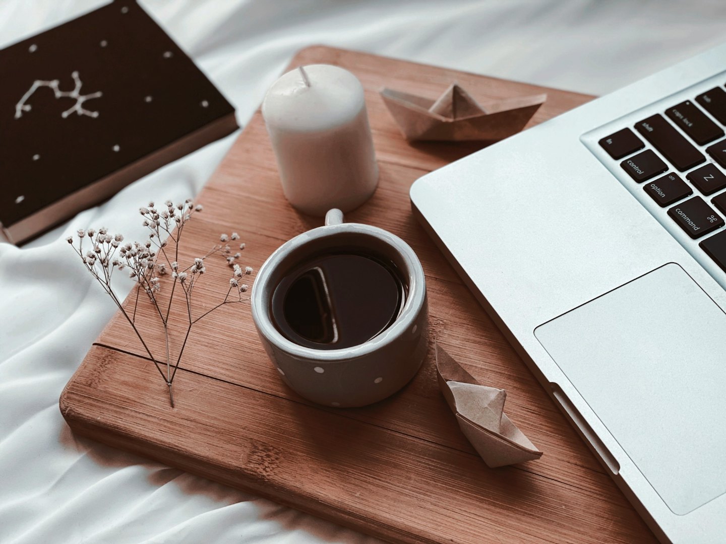 Laptop and coffee on a wooden board with decorative items.