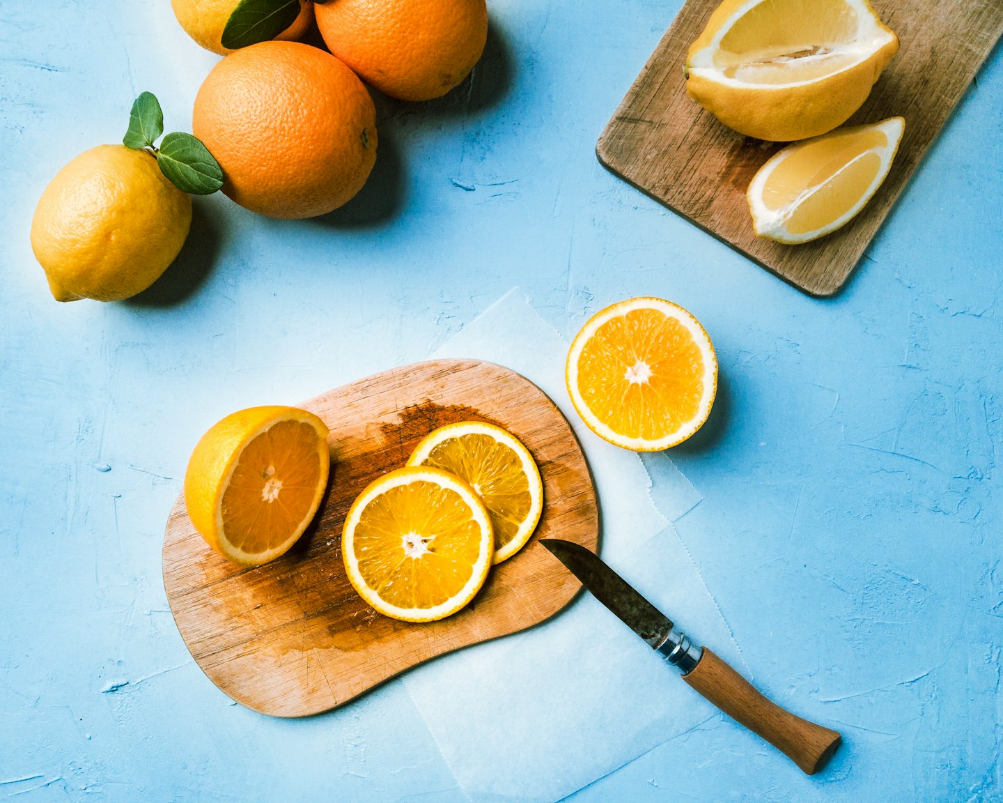 Lemons and oranges sliced and whole on cutting boards.