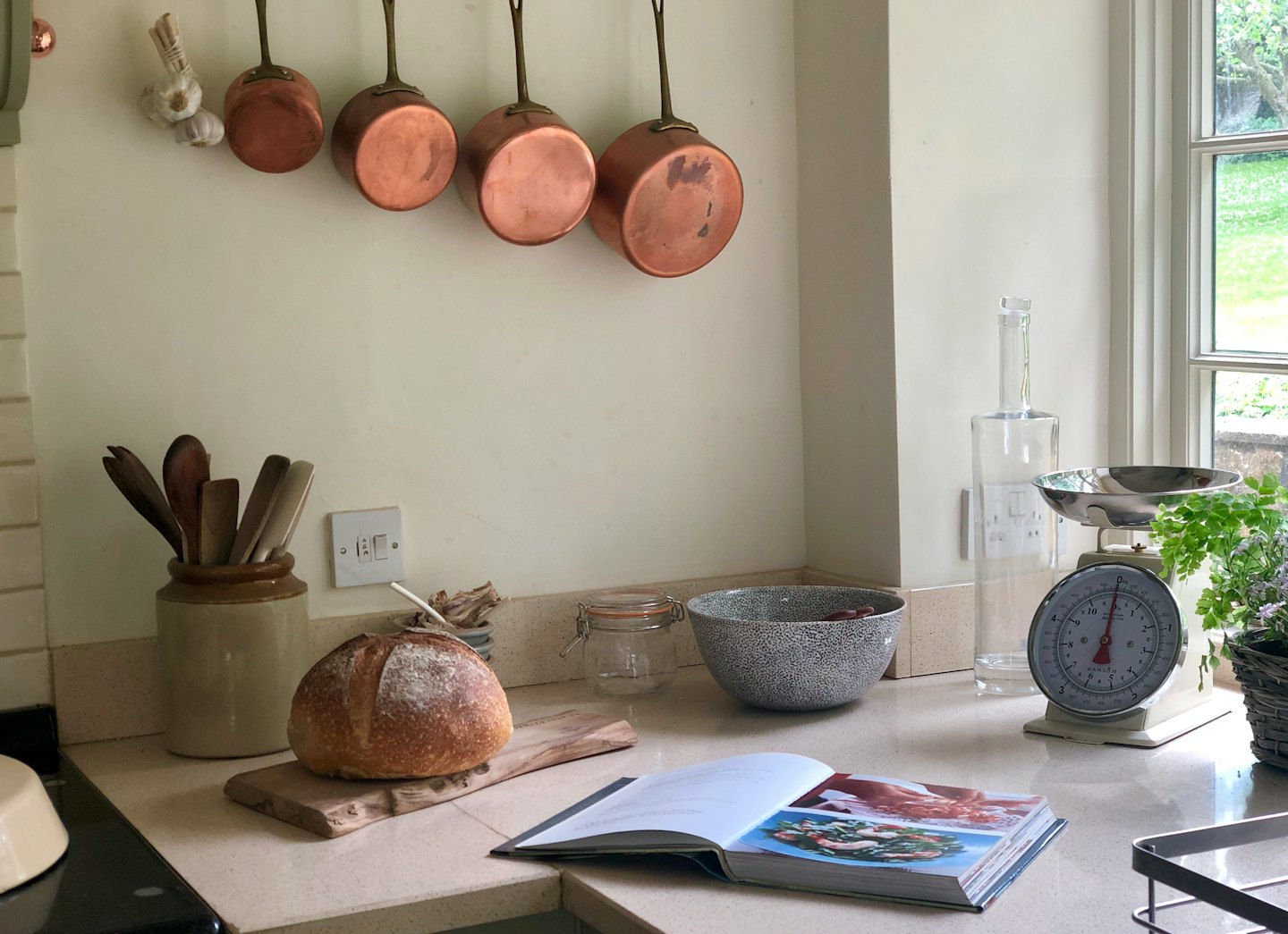 Rustic kitchen counter with sourdough bread and cooking utensils.