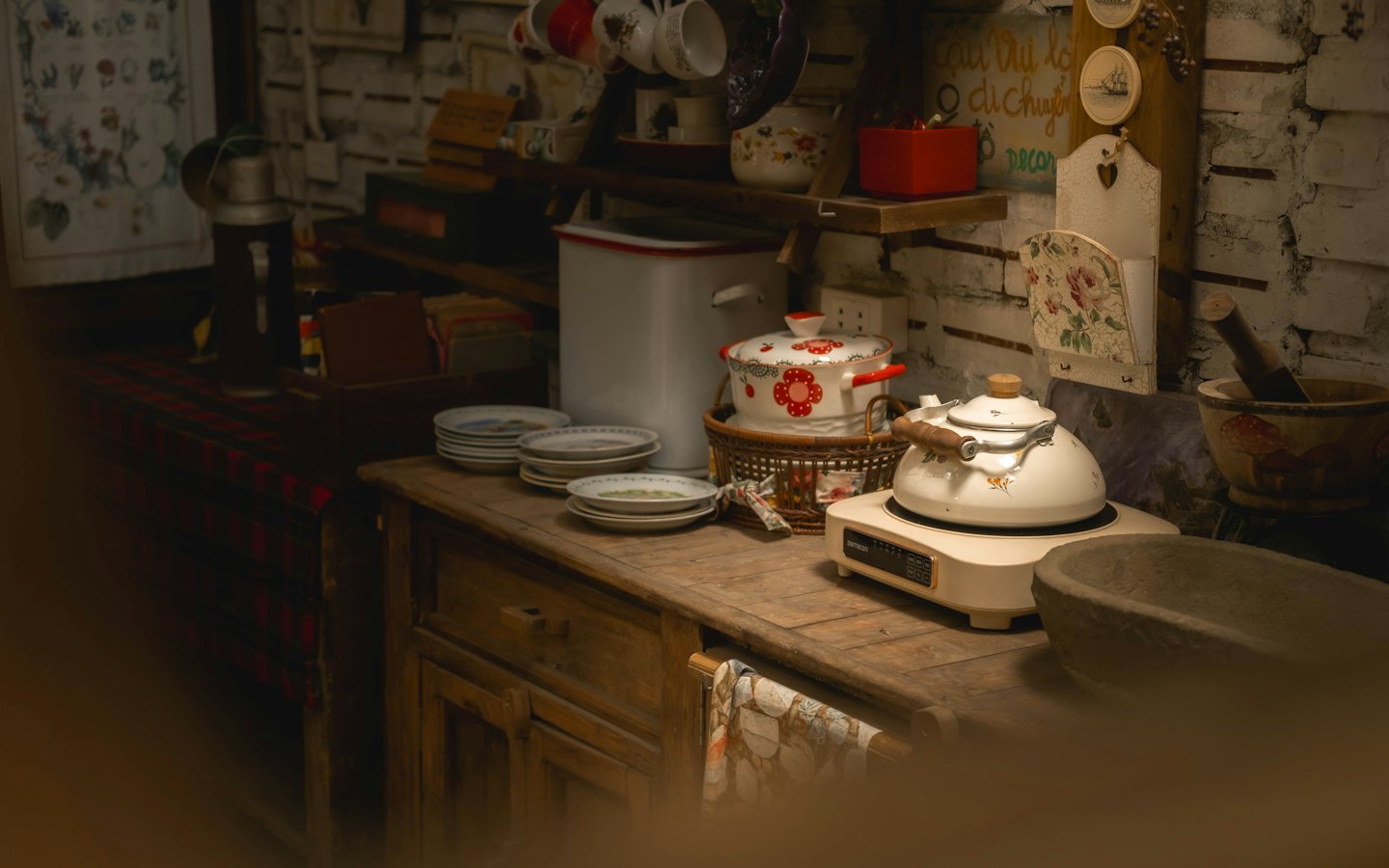 Vintage kitchenware on a rustic counter against a brick wall.