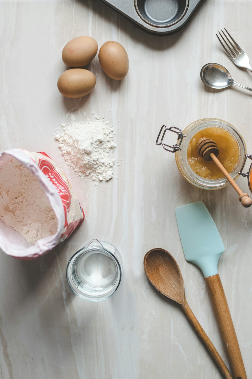 Baking ingredients and tools laid out on a marble countertop.